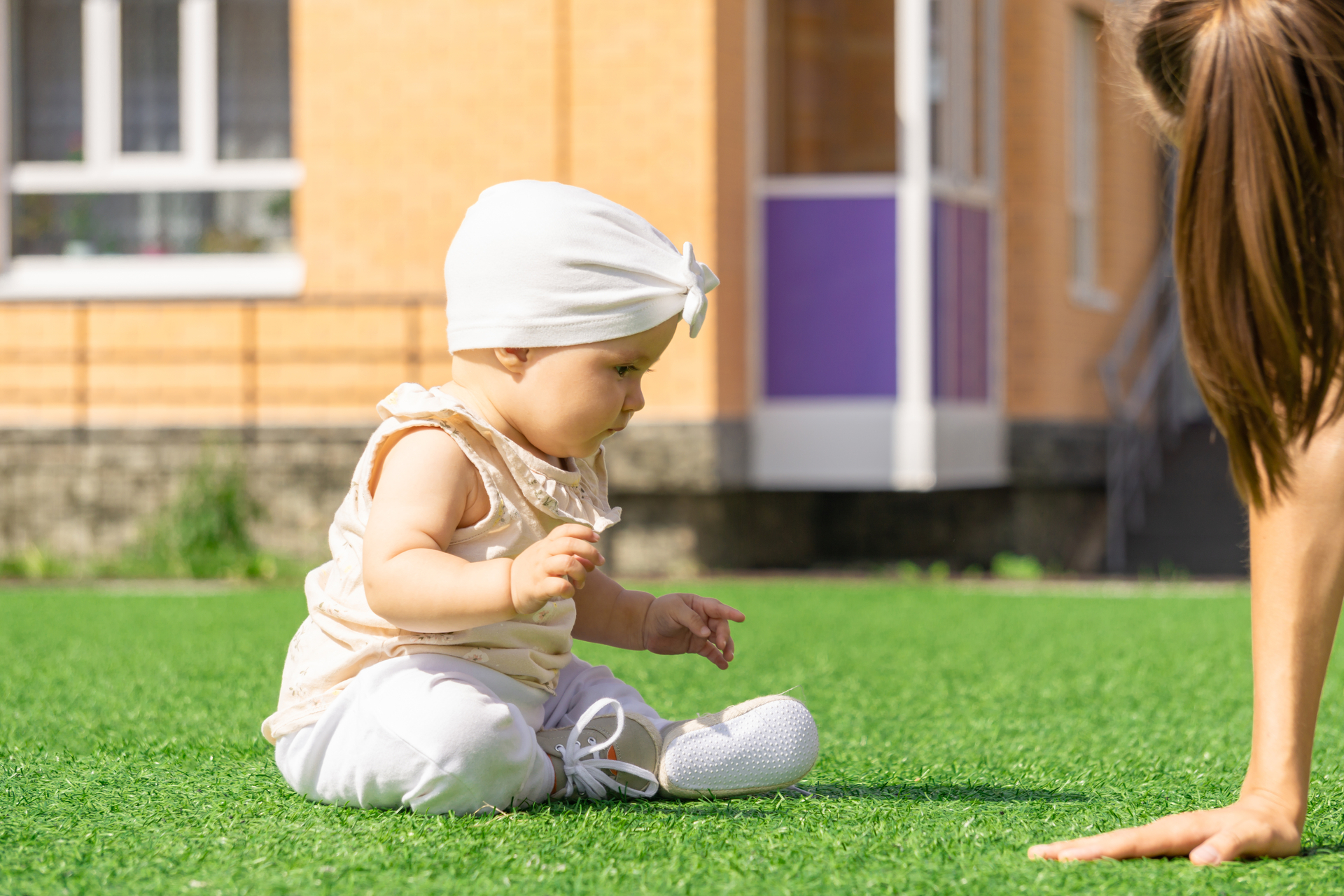 Infant playing with mother on artificial grass - Orion Turf and Landscape