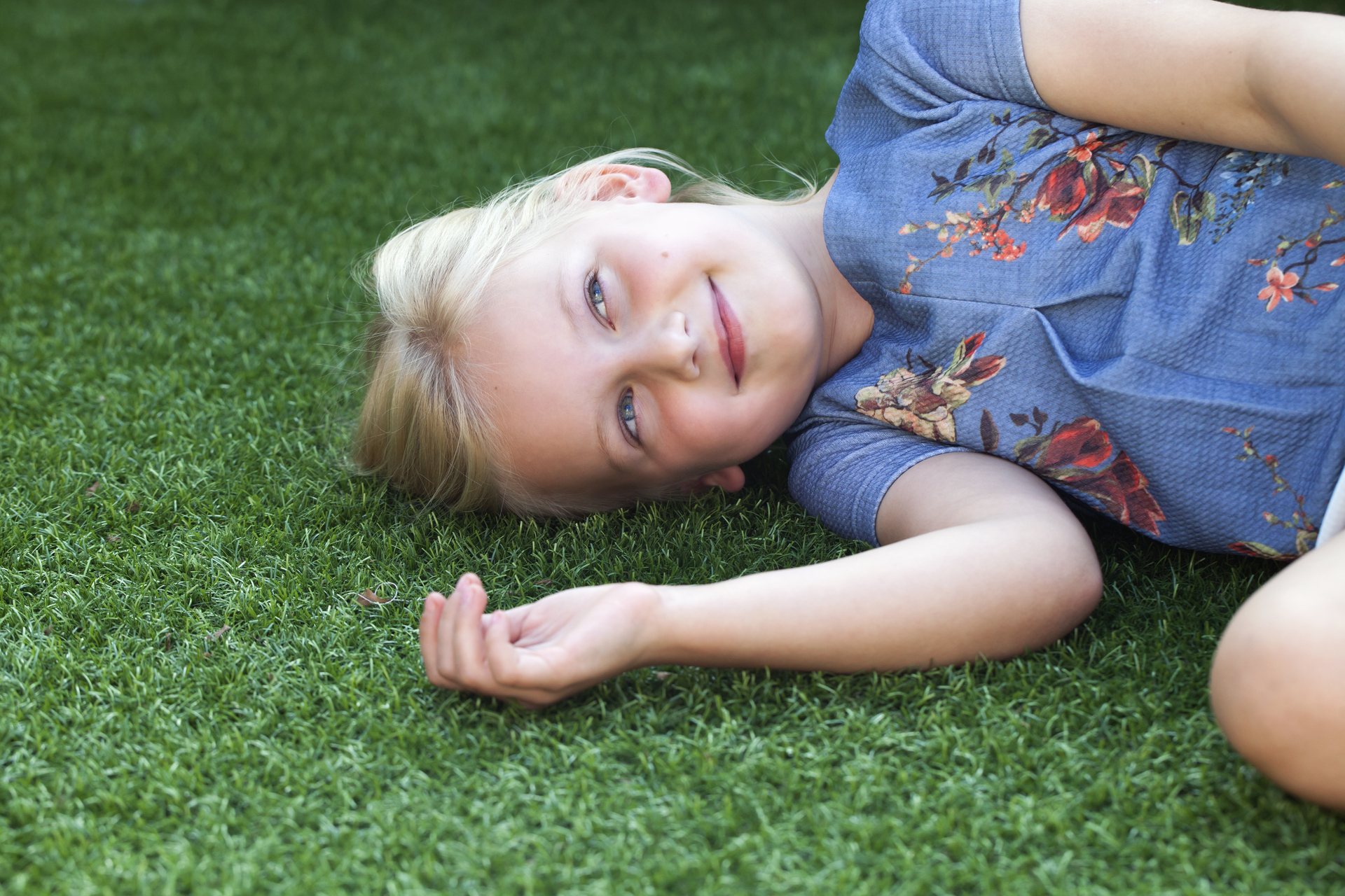 Kid smiling and laying on artificial grass - Orion Turf and Landscape